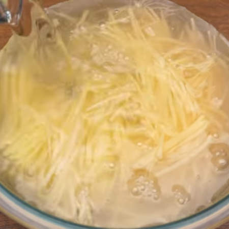 Натертый картофель перекладываем в миску и заливаем холодной водой.