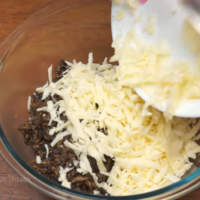 Натертый сыр добавляем к остывшим грибам. 