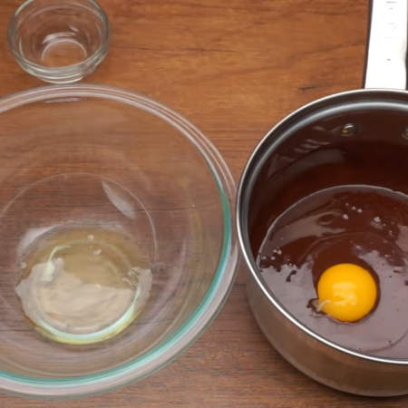 Одно яйцо разделяем на желток и белок.
Белок выливаем в чистую и обязательно сухую миску, а желток добавляем к шоколадной массе.
Шоколадную массу с желтком сразу же хорошо размешиваем лопаткой.