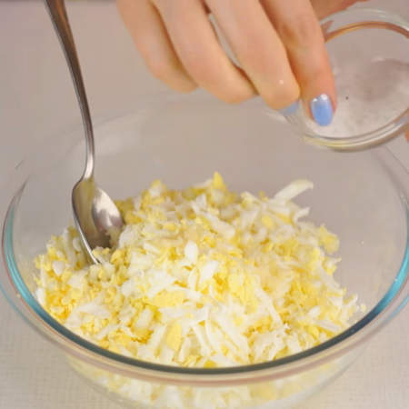В миску к сыру натираем вареные яйца на крупной терке.
Начинку солим по вкусу. 