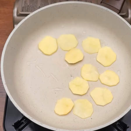 На разогретую сковороду наливаем немного растительного масла. Кладем пластинки картофеля. 