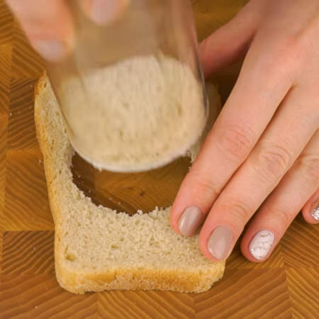 Для каждого бутерброда понадобится 2 ломтика хлеба. В одном из них вырезаем кружок с помощью стакана.