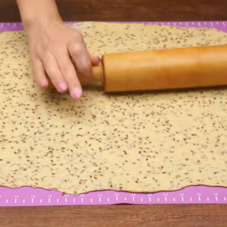 Готовое тесто раскатываем в прямоугольный лист немного припыляя мукой коврик.
Тесто раскатываем как можно тоньше. Толщина теста должна получиться не больше 2-х мм, тогда крекер получится вкусным и хрустящим.
