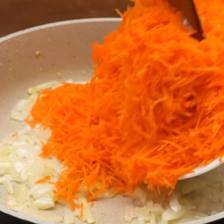 К луку добавляем тертую морковь и пассеруем еще примерно 1 минуту.