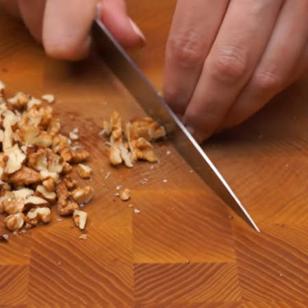 50 г грецких орехов нарезаем ножом на более мелкие кусочки.
