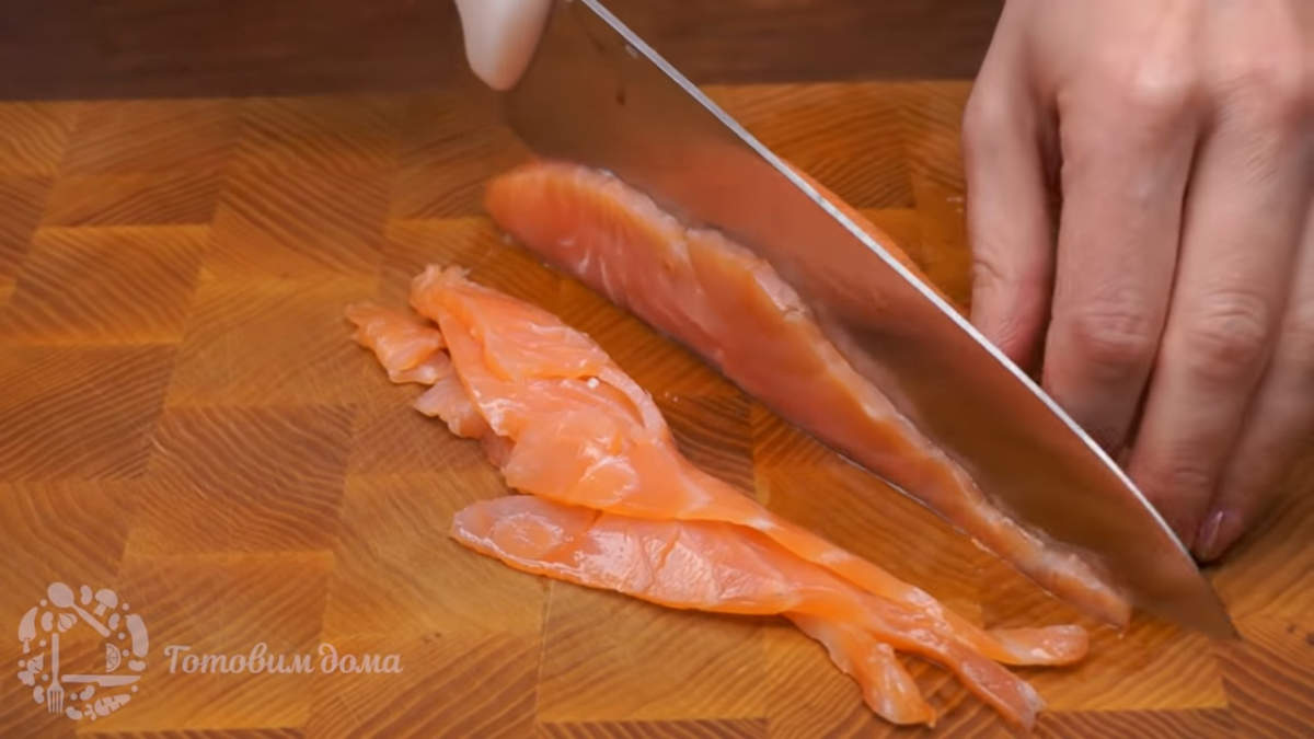 200 г соленой красной рыбы нарезает тонкими пластинками.