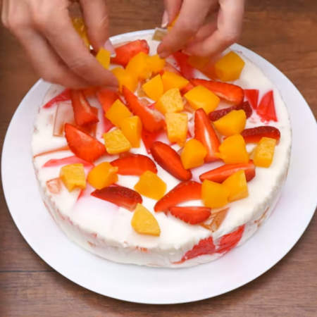Сверху на торт выкладываем кусочки персиков и клубники. 