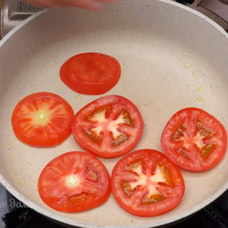 Разогретую сковороду немного смазываем растительным маслом и выкладываем кружочки помидоров.
Помидоры тоже обжариваем примерно по полминуты с двух сторон.