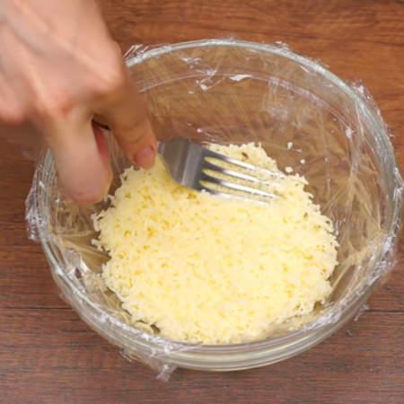 Складываем салат.
Первым слоем кладем половину тертого сыра и немного утрамбовываем его вилкой.