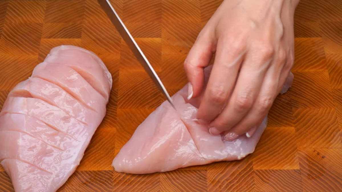 Сначала подготовим мясо.
Две куриные грудки, общим весом примерно 500 г моем и делаем на них поперечные надрезы. Прорезаем ножом до середины куска.