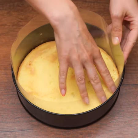 В форму в которой пекся бисквит ставим по кругу ацетатную пленку и кладем на дно подготовленный бисквит.