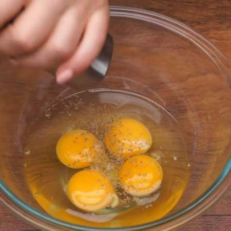 Приготовим яичницу для начинки.
В миску разбиваем 4 яйца. Яйца солим по вкусу и перчим.