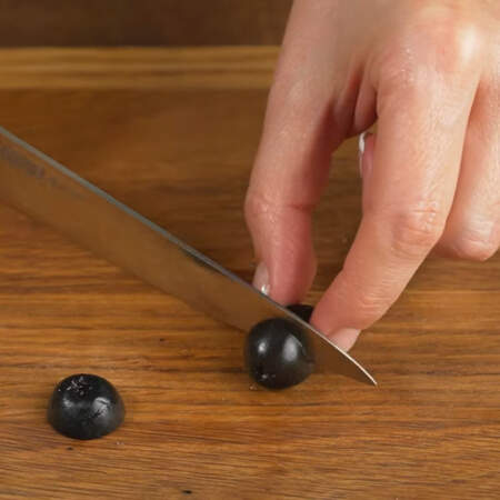 Берем черные оливки без косточки и отрезаем небольшие  кружочки сначала с одной стороны,