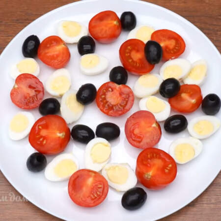 Складываем салат.
На большое плоское блюдо выкладываем часть помидоров черри.
Часть перепелиных яиц, половину черных маслин.
