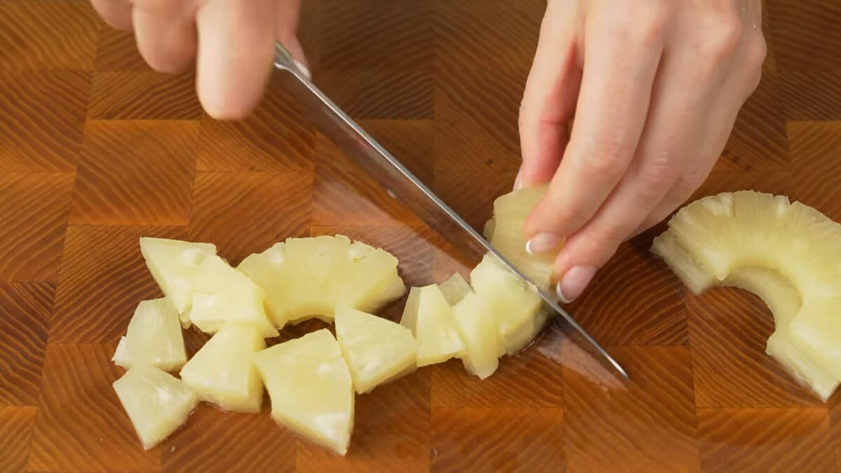 Пока маринуется филе подготовим остальные ингредиенты.
Консервированные кольца ананаса нарезаем на кусочки. Также можно взять уже нарезанные ананасы кусочками.
