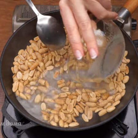 Когда арахис уже обжарился до нужного состояния, выливаем к нему воду с сахаром. 