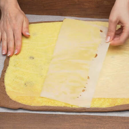 Испекшийся бисквит вытаскиваем из духовки и сразу же переворачиваем на расстеленный лист пергаментной бумаги. Бумагу на которой пекся бисквит снимаем.