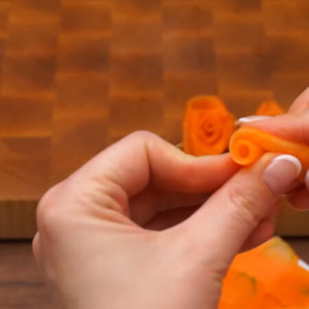 Из остывших морковных полосок скручиваем цветы.
Сначала скручиваем пластинку морковки в небольшую трубочку.