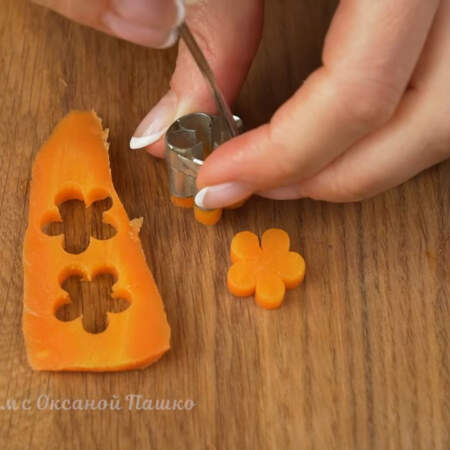 Из пластинки отварной морковки с помощью вырубки вырезаем три цветочка.