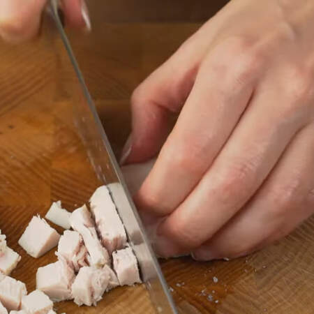 Вареное мясо нарезаем сначала пластинками, а затем пластинки разрезаем на небольшие кубики.