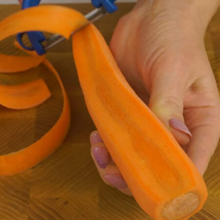 Теперь займемся украшением салата. Берем сырую морковь и овощечисткой нарезаем ее на тонкие полосы. 