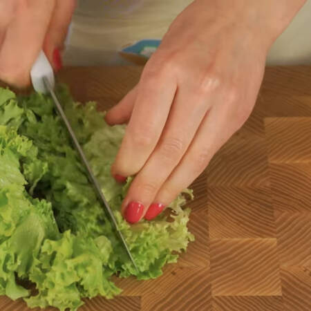 Листья салата нарезаем ножом на не сильно мелкие куски, чтобы не выжать сок из листьев. Также можно порвать салат руками.