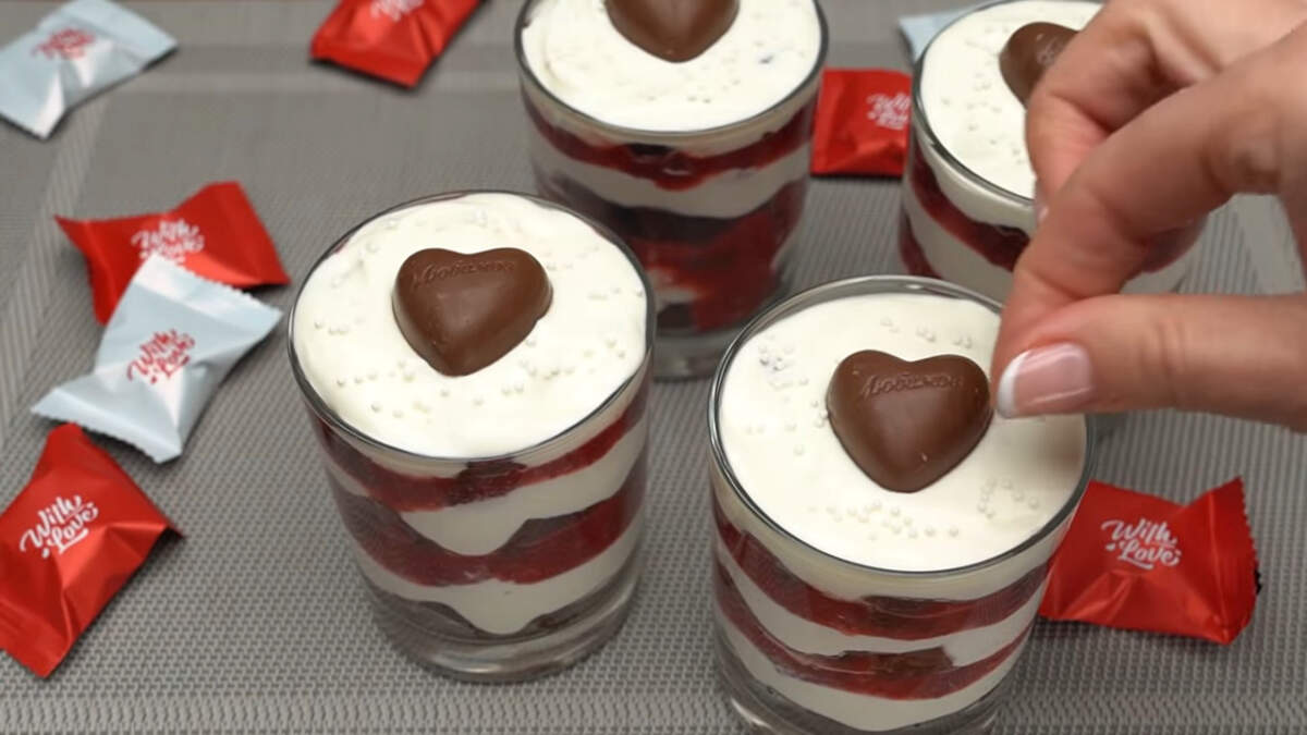 Сверху десерты украшаем шоколадными конфетами в виде сердечка. Сметанный крем посыпаем белой сахарной посыпкой.
