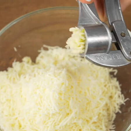 В миску к тертому сыру добавляем 2 зубчика чеснока через пресс,