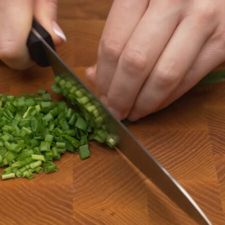 Из пучка зеленого лука выбираем 5-7 красивых перьев, они нам понадобятся для украшения салата. Остальной зеленый лук мелко нарезаем ножом.