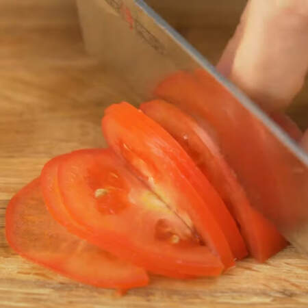 Для украшения блюда приготовим цветок из помидора.
1 помидор среднего размера разрезаем вдоль пополам. Половинку помидора нарезаем тонкими пластинками. Чем тоньше пластинки, тем удобнее будет заворачивать розу.
