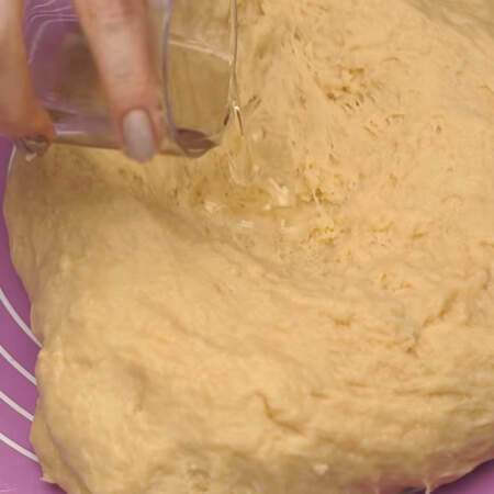 В уже замешенное тесто в несколько подходов добавляем 50 г подсолнечного масла. 
