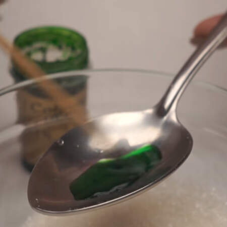Сделаем цветной сахар для украшения. 
Берем столовую ложку сахара и насыпаем в мисочку. В ложку наливаем несколько капель воды и растворяем в ней пищевой краситель. 