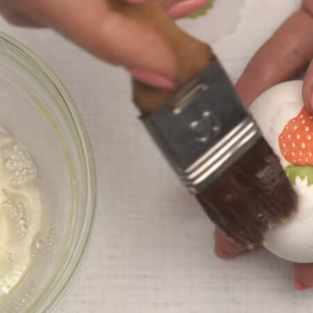 Вырезанный рисунок кладем на вареное яйцо и кисточкой, смоченной белком приклеиваем его сверху.
Так украшаем все яйцо.
