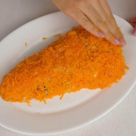 Весь салат покрываем тертой морковкой и выравниваем вилкой. 