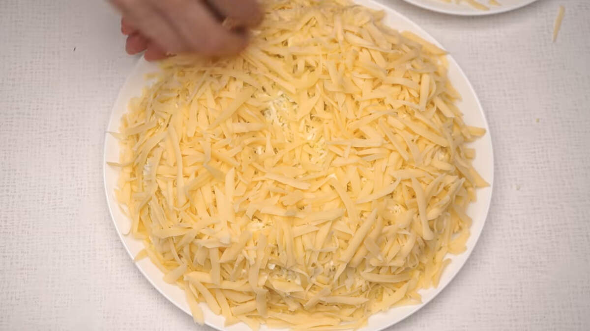 И последним слоем выкладываем тертый сыр покрывая салат сверху и по бокам.
