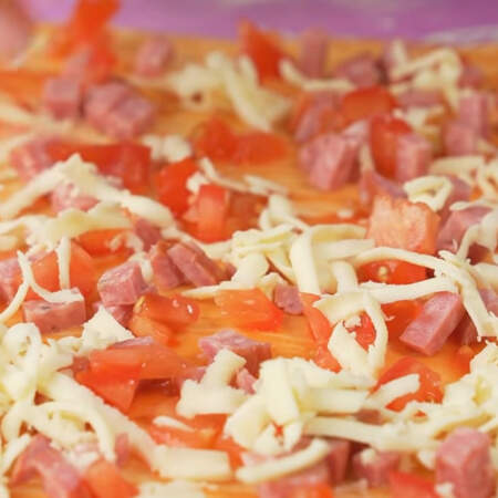Равномерно посыпаем нарезанной колбасой. Раскладываем подготовленные кусочки помидоров. Сверху все посыпаем тертым сыром.
