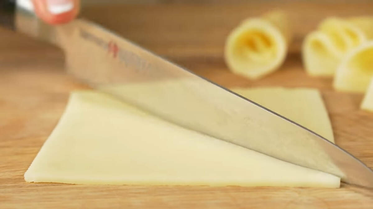Третьими приготовим бутерброды с сыром.
Берем тонкие ломтики сыра и разрезаем их по диагонали. Я использую уже нарезанный сыр.

