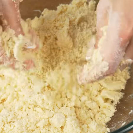 Масло сначала обваливаем в муке ложкой, а затем перетираем его руками в крошку. Это нужно делать достаточно быстро, чтобы масло как можно меньше нагрелось от тепла рук.
