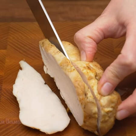 300 г запеченного куриного филе нарезаем сначала пластинками.