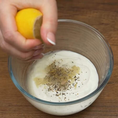 Готовим заправку.
В миску наливаем 200 мл густого йогурта, солим примерно половиной ч. л. соли, выдавливаем через пресс 2-3 зубчика чеснока и перчим черным молотым перцем. Сюда же выдавливаем примерно 2-3 ст.л. лимонного сока. 
