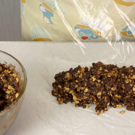 Из получившейся шоколадной массы формируем кондитерские колбаски. 
Для этого на столе расстилаем пищевую пленку и выкладываем на нее половину приготовленной массы. 