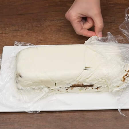 Торт застыл. Снимаем пищевую пленку и переворачиваем его на блюдо. С торта аккуратно снимаем пленку. Б