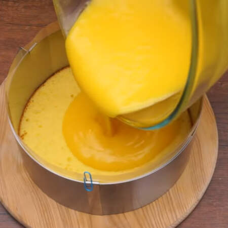 Торт будем собирать в раздвижном кулинарном кольце. Первый корж кладем в кольцо и ставим вокруг него ацетатную пленку. Кольцо сжимаем до тех пор, пока пленка плотно не прижмется к бисквиту.
Сверху на бисквит наливаем половину остывшего лимонного крема. 
