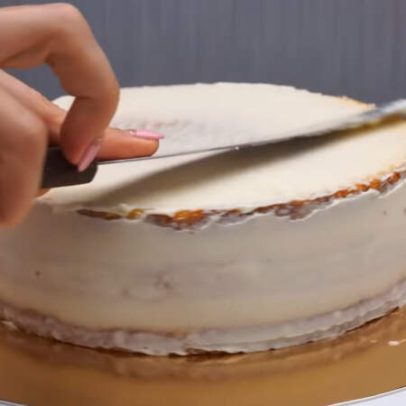 По бокам и сверху торт обмазываем кремом и выравниваем шпателем. Сначала наносим черновой слой крема, чтобы убрать крошки,