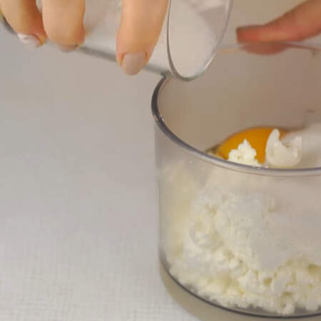 Сначала замесим творожное тесто для коржей. Творог перекладываем в чашу измельчителя, добавляем одно яйцо и 150 г сахара. 