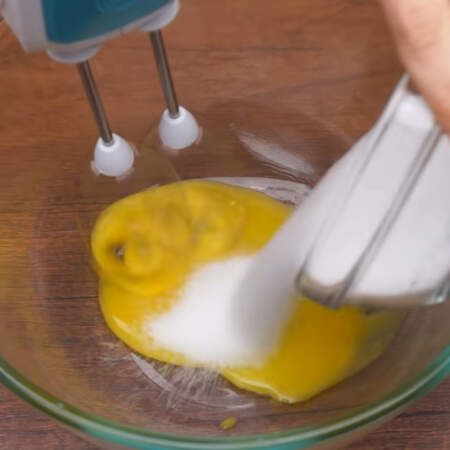 Пока закипает молоко готовим остальную часть крема.
В миску выливаем 2 желтка и начинаем взбивать миксером.  Постепенно к желткам добавляем 4 ст. л. сахара и 15 г ванильного сахара. 