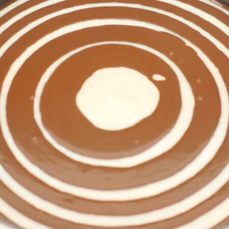 Так как шоколадной массы получилось больше, то ее выливаем по 6 ст. л., а белой по 5 ст. л. Массу нужно выливать очень аккуратно и четко в центр формы.