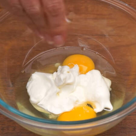 В миску разбиваем 2 яйца, добавляем 100 мл сметаны и солим по вкусу. 
