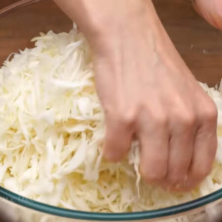 Нашинкованную капусту перекладываем в миску. Капусту солим по вкусу. Все перемешиваем немного перетирая руками с солью.
