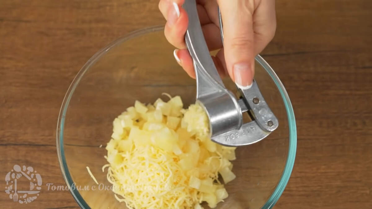 В миску к сыру добавляем нарезанные ананасы. Сюда же выдавливаем через пресс 1 зубчик чеснока.